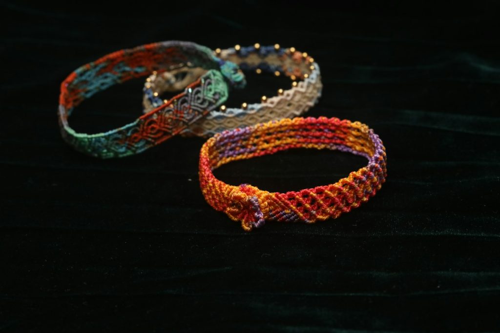 Three colorful woven bracelets on dark fabric